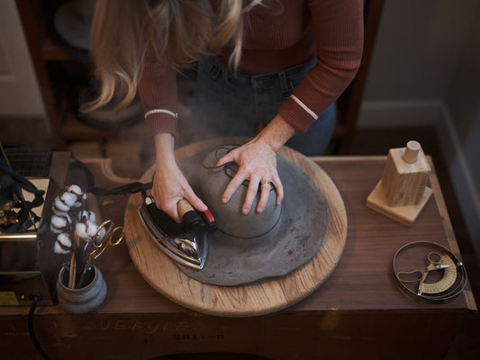 Woman shapes a hat with an iron.
