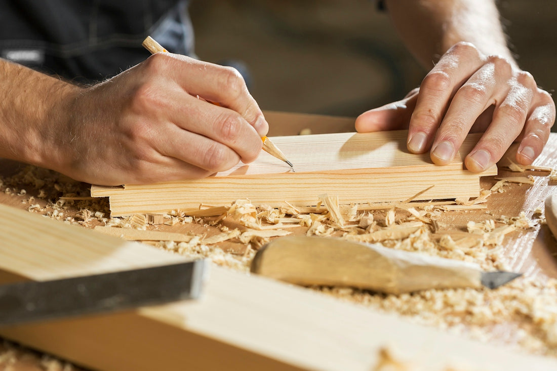 A person marking a line on a wooden board with a pencil