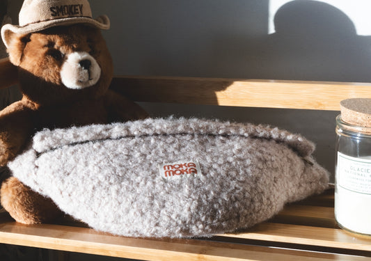 a brown teddy bear sitting on top of a wooden shelf