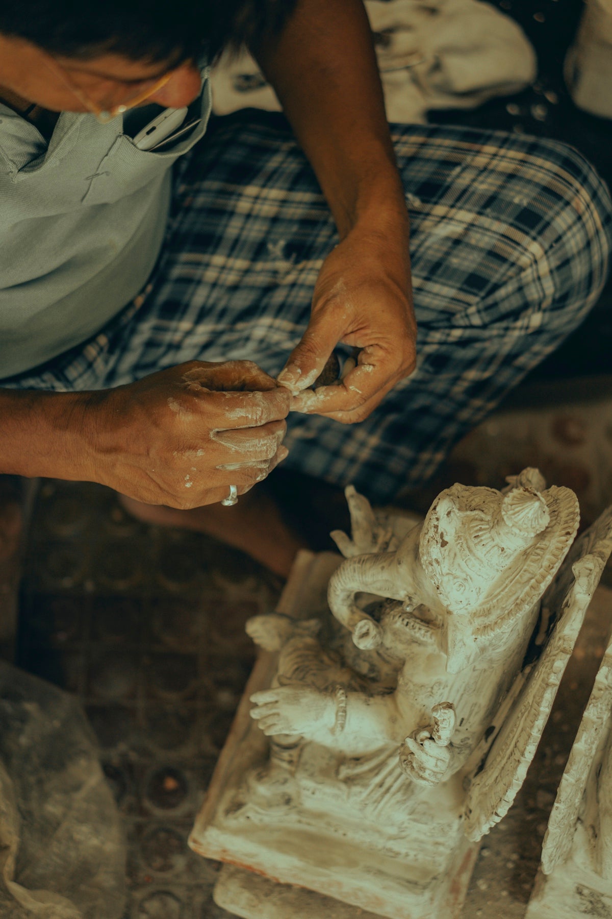 A man is carving a statue with a mask on