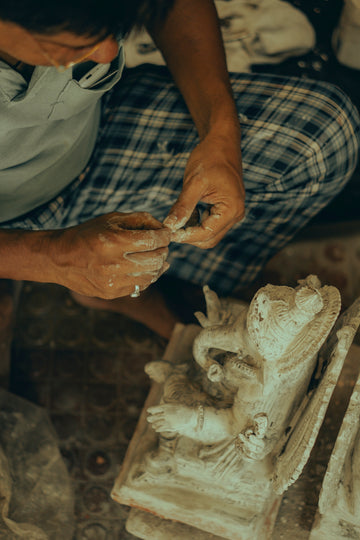 A man is carving a statue with a mask on