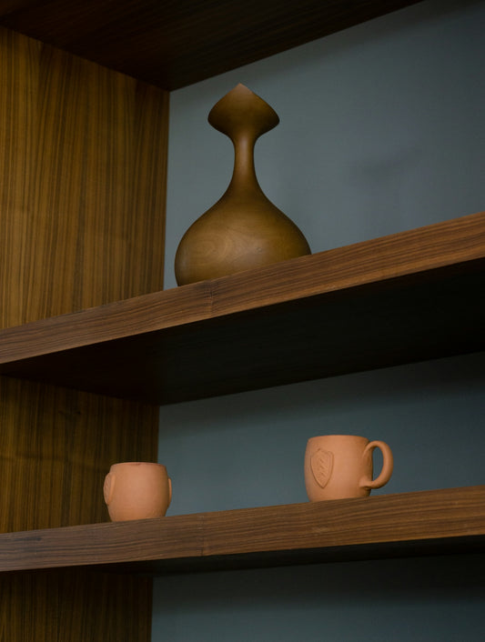 Decorative wooden vase and two terracotta mugs on shelves